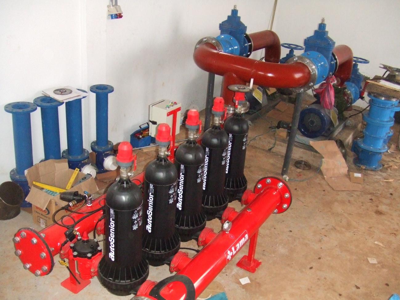 Filtros AutoSenior negros y tuberías rojas y azules en una sala de instalación o almacenamiento de equipos hidráulicos.
